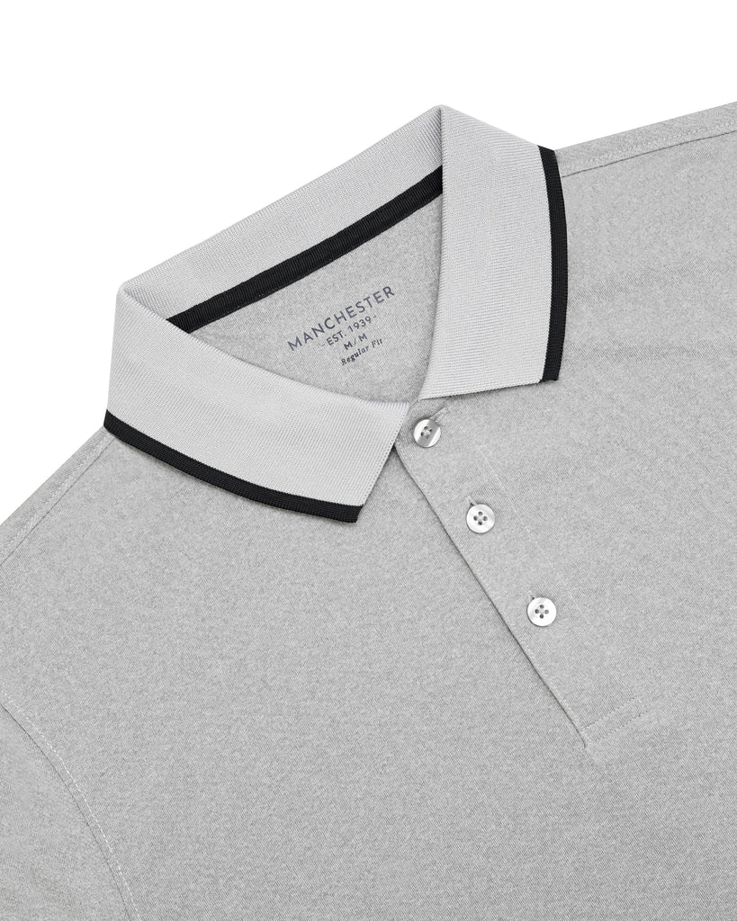 Camisa polo gris claro con cuello clásico y tres botones, perfecta para combinar con jeans o pantalón deportivo